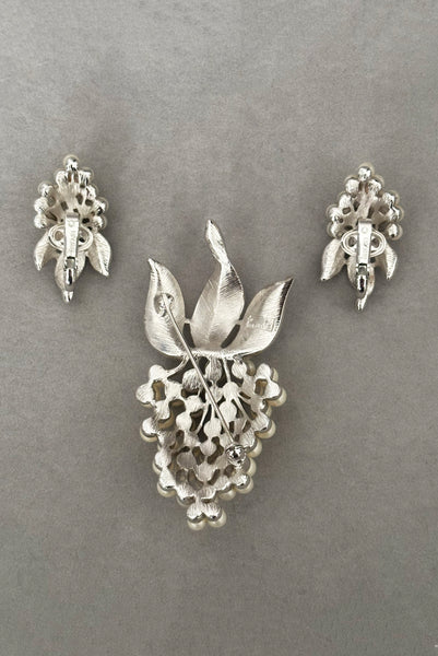 Vertical back view of 1960s vintage Crown Trifari white pearl silver tone grape cluster brooch and clip-on earrings jewelry set.