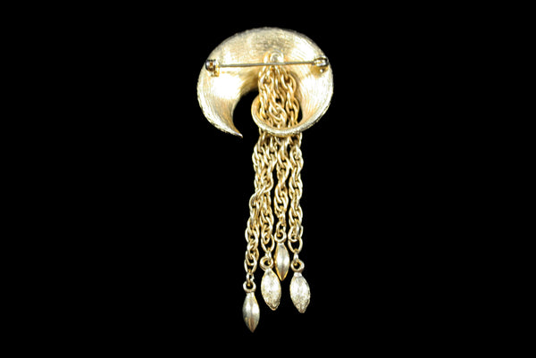 Horizontal back view of 1960s vintage round swirl gold tone brooch with chain tassel.