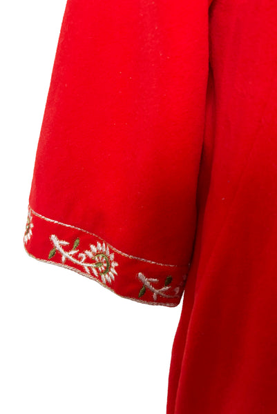 Detail view of 1960s vintage orange fleece, zip front housecoat with white, green, and gold floral embroidery by Evelyn Parsons, size medium to large. Showing the long bell sleeves with floral embroidered cuffs.
