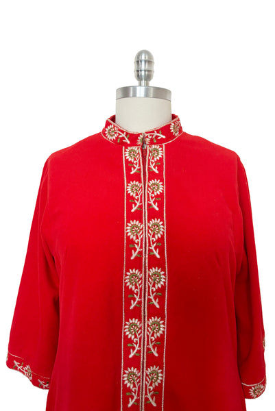 Bodice front view of 1960s vintage orange fleece, zip front housecoat with white, green, and gold floral embroidery by Evelyn Parsons, size medium to large. Showing the band collar, zipper placket, and cuffs with floral embroidery.