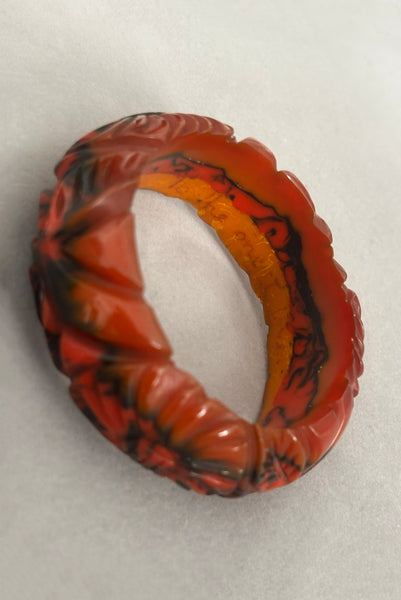 Detail view of 1940s vintage butterscotch, black, and red  floral carved end of day Bakelite bangle bracelet. Inscribed: "to the one I love". Showing the inscription on the inside of the bangle.