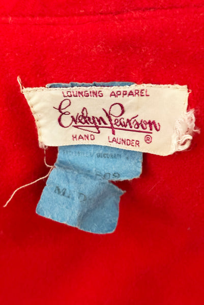 Interior detail view of 1960s vintage orange fleece, zip front housecoat with white, green, and gold floral embroidery by Evelyn Parsons, size medium to large. Showing the Evelyn Parsons label and size Med tag.