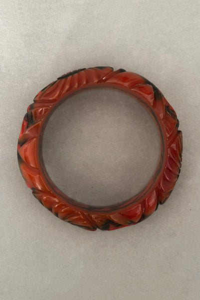 Vertical top view of 1940s vintage butterscotch, black, and red  floral carved end of day Bakelite bangle bracelet. Inscribed: "to the one I love".