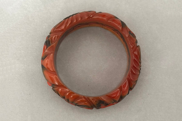 Horizontal top view of 1940s vintage butterscotch, black, and red  floral carved end of day Bakelite bangle bracelet. Inscribed: "to the one I love".