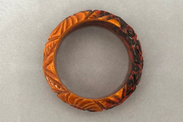 Horizontal bottom view of 1940s vintage butterscotch, black, and red  floral carved end of day Bakelite bangle bracelet. Inscribed: "to the one I love".