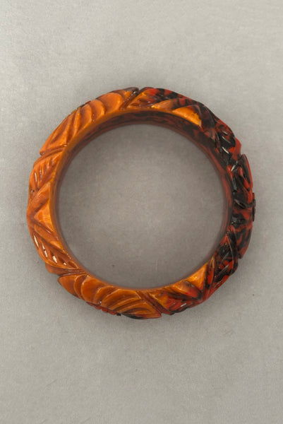 Vertical bottom view of 1940s vintage butterscotch, black, and red  floral carved end of day Bakelite bangle bracelet. Inscribed: "to the one I love".