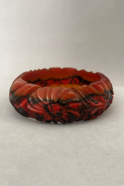 Vertical front view of 1940s vintage butterscotch, black, and red  floral carved end of day Bakelite bangle bracelet. Inscribed: "to the one I love".
