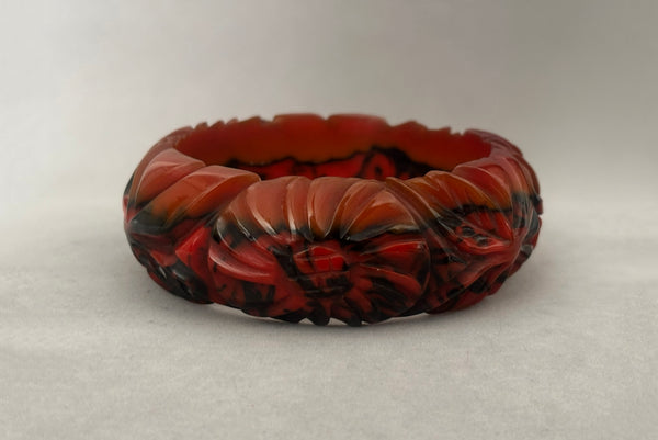 Horizontal front view of 1940s vintage butterscotch, black, and red  floral carved end of day Bakelite bangle bracelet. Inscribed: "to the one I love".