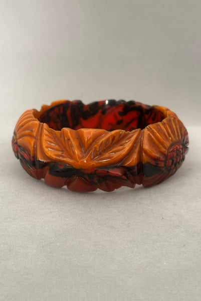 Vertical side view of 1940s vintage butterscotch, black, and red  floral carved end of day Bakelite bangle bracelet. Inscribed: "to the one I love".