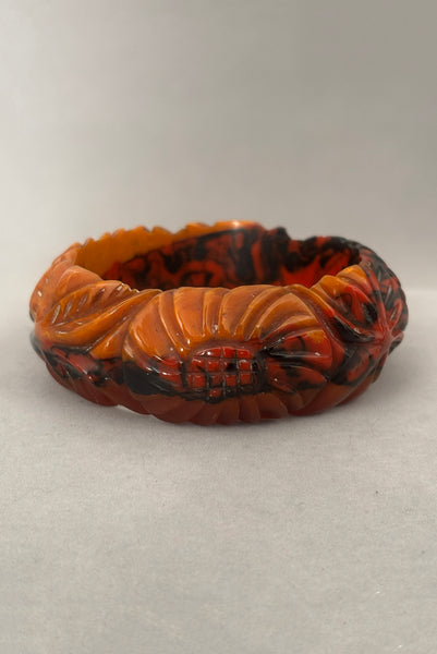 Vertical back view of 1940s vintage butterscotch, black, and red  floral carved end of day Bakelite bangle bracelet. Inscribed: "to the one I love".
