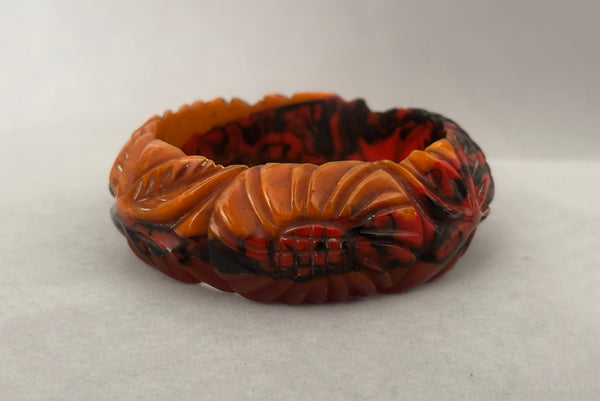 Horizontal back view of 1940s vintage butterscotch, black, and red  floral carved end of day Bakelite bangle bracelet. Inscribed: "to the one I love".