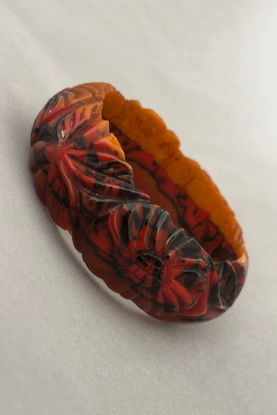Vertical perspective view of 1940s vintage butterscotch, black, and red  floral carved end of day Bakelite bangle bracelet. Inscribed: "to the one I love".