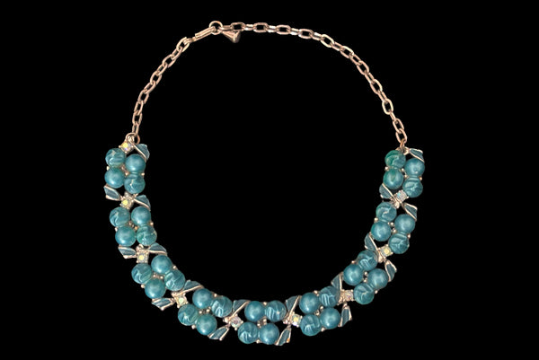 Horizontal front view of 1950s vintage teal blue textured plastic bead and iridescent rhinestone silver tone necklace.