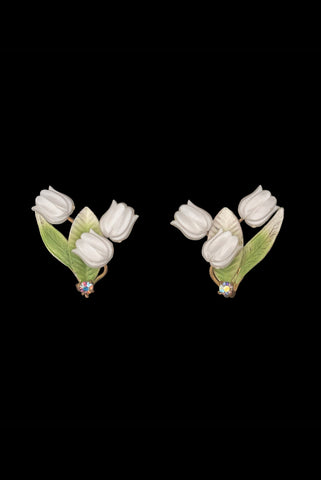 Vertical front view of 1950s vintage iridescent rhinestone, white plastic tulip, green and white painted floral gold tone metal clip-on earrings.