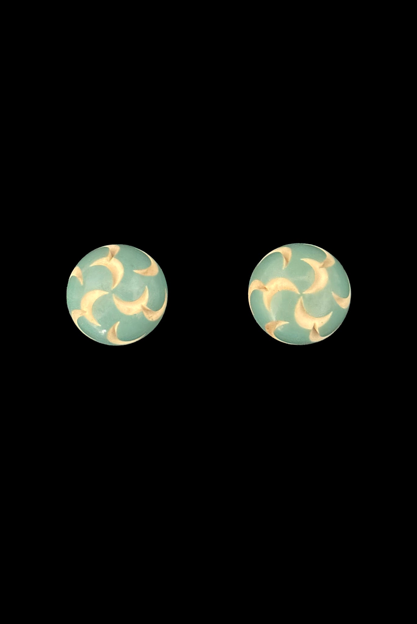Vertical front view of 1930s vintage cut through aqua blue resin washed cream carved Bakelite screw-back button earrings.