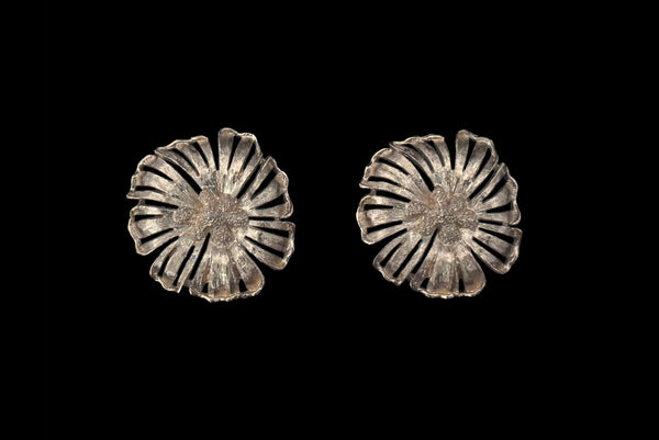 Horizontal front view of 1960s vintage large round gold tone floral clip-on earrings by Monet.