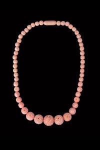 Vertical view of 1930s vintage floral carved coral pink celluloid graduated bead necklace.