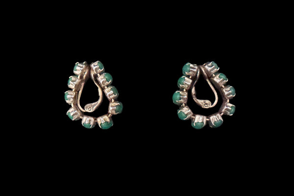 Horizontal side view of 1950s vintage green marquise cabochon gold tone clip -on hoop earrings.