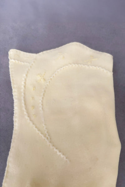 Detail view of 1950s vintage pastel yellow cotton wrist length curved cuff embroidered gloves. Approximately size 7.5. Showing a close-up of the curved cuff with puckered decorative stitching and embroidered sprigs. One small break in the decorative stitching.