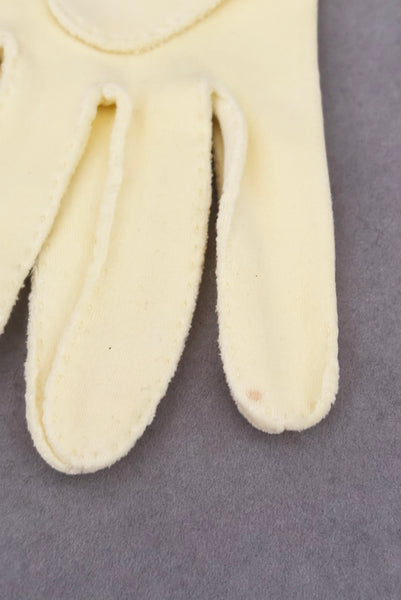 Detail view of 1950s vintage pastel yellow cotton wrist length curved cuff embroidered gloves. Approximately size 7.5. Showing a close-up of a small brown dot on an interior finger of the left glove.