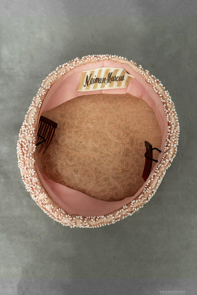 Vertical interior view of 1960s vintage blush pink faille fabric pillbox hat covered in matching glass seed beads by Neiman Marcus.
