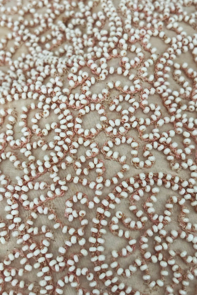 Detail view of 1960s vintage blush pink faille fabric pillbox hat covered in matching glass seed beads by Neiman Marcus. Showing a close up of the meandering beading.