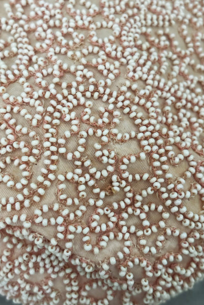 Detail view of 1960s vintage blush pink faille fabric pillbox hat covered in matching glass seed beads by Neiman Marcus. Showing a close up of the meandering beading.