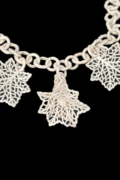 Detail view of 1930s vintage cream lace look floral and leaf celluloid plastic statement necklace. Showing a close up of the 3-dimensional flowers and leaves.