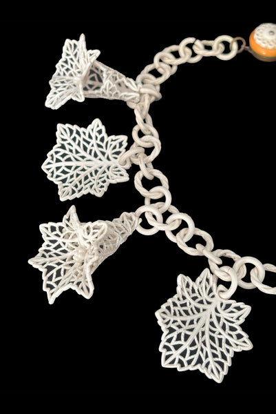 Detail view of 1930s vintage cream lace look floral and leaf celluloid plastic statement necklace. Showing a close up of the 3-dimensional flowers and leaves.