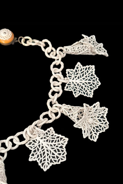 Detail view of 1930s vintage cream lace look floral and leaf celluloid plastic statement necklace. Showing a close up of the 3-dimensional flowers and leaves.