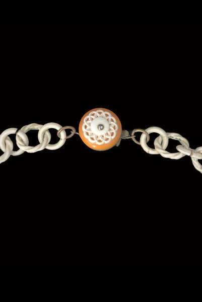 Detail view of 1930s vintage cream lace look floral and leaf celluloid plastic statement necklace. Showing a close up of the front of the Bakelite, celluloid, and brass clasp.