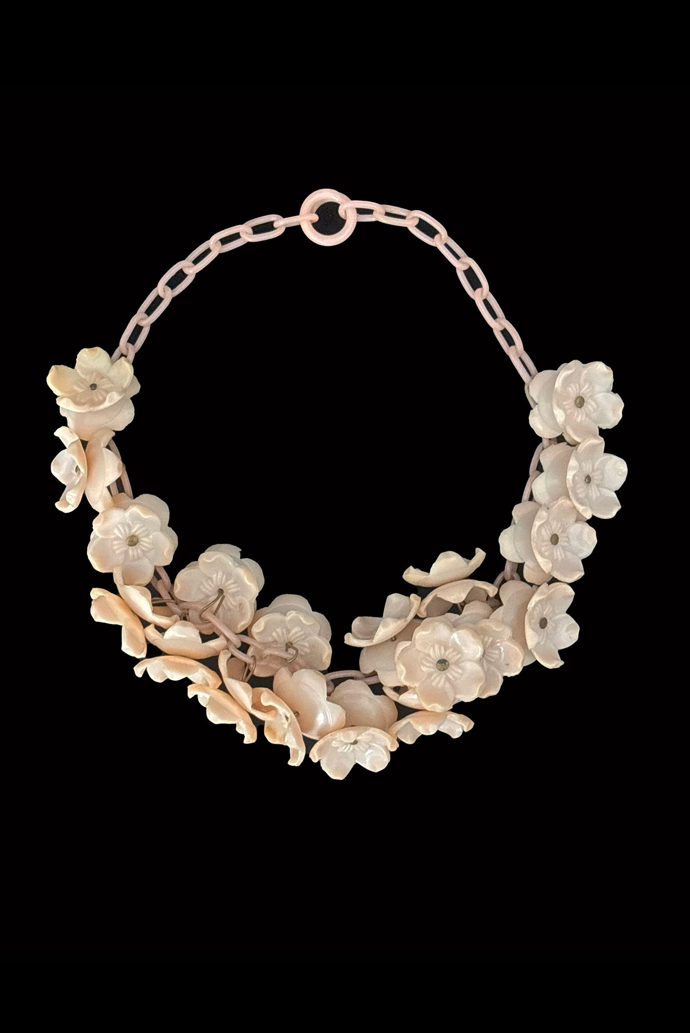 Vertical front view of 1930s vintage blush pink three-dimensional floral celluloid plastic statement necklace.