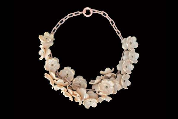 Horizontal front view of 1930s vintage blush pink three-dimensional floral celluloid plastic statement necklace.