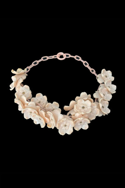 Vertical perspective view of 1930s vintage blush pink three-dimensional floral celluloid plastic statement necklace.
