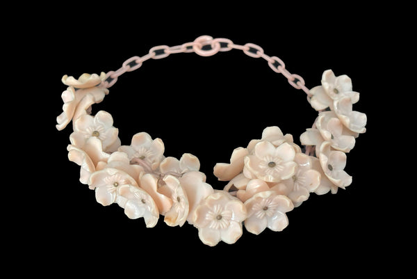 Horizontal perspective view of 1930s vintage blush pink three-dimensional floral celluloid plastic statement necklace.