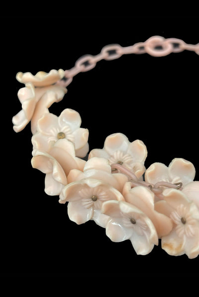 Detail view of 1930s vintage blush pink three-dimensional floral celluloid plastic statement necklace. Showing a close-up of the flowers mounted on brass pins.