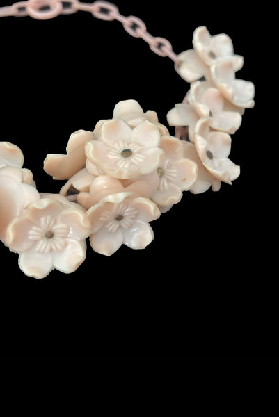 Detail view of 1930s vintage blush pink three-dimensional floral celluloid plastic statement necklace. Showing a close-up of the flowers mounted on brass pins.