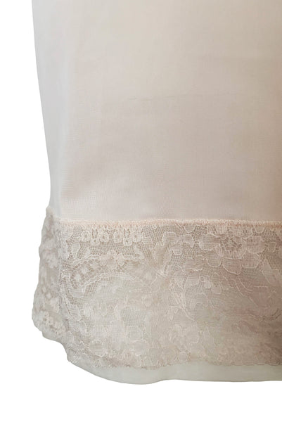 Detail view of 1950s vintage pale pastel pink nylon half slip with mesh and lace hem by Komar Lingerie, size small to medium.