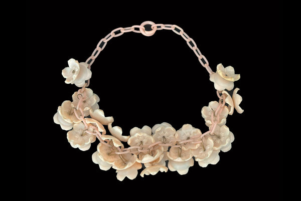 Horizontal back view of 1930s vintage blush pink three-dimensional floral celluloid plastic statement necklace.
