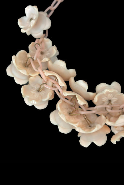Detail view of 1930s vintage blush pink three-dimensional floral celluloid plastic statement necklace. Showing a close-up of the flowers mounted on brass pins.