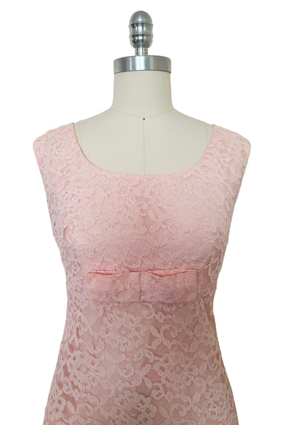 Bodice front view of 1960s vintage pink lace Mod empire waist cocktail shift dress, size medium to large. Showing the scoop neckline and bow at the waist.