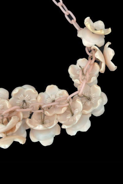 Detail view of 1930s vintage blush pink three-dimensional floral celluloid plastic statement necklace. Showing a close-up of the flowers mounted on brass pins.