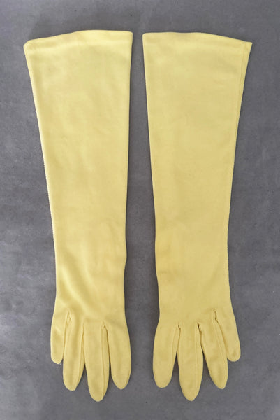 Vertical front view of 1950s vintage below elbow yellow nylon gloves by Hansen. Size 6.