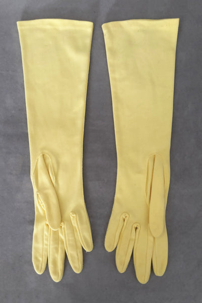 Vertical back view of 1950s vintage below elbow yellow nylon gloves by Hansen. Size 6.