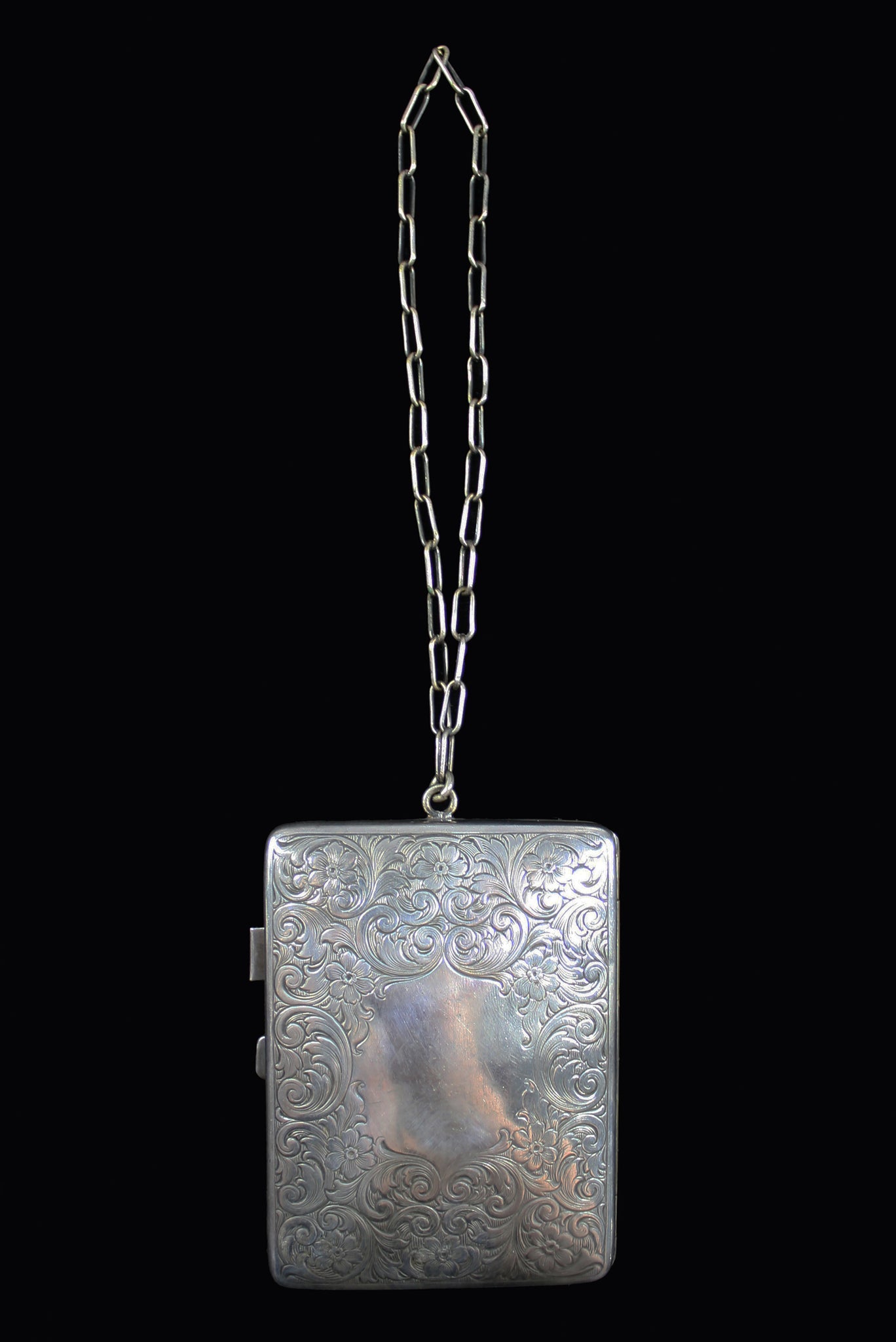 Vertical front view of 1910s to 1920s vintage floral engraved German silver compact dance bag.