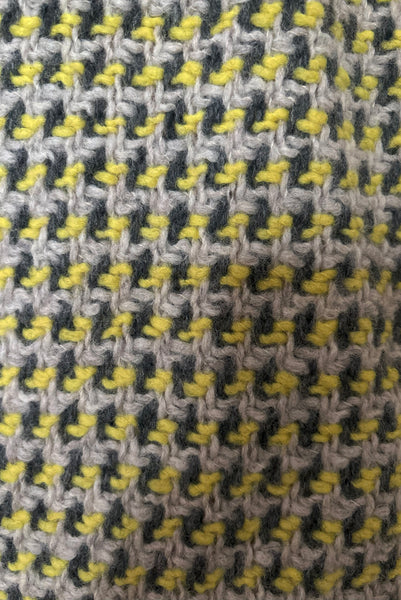 Detail view of 1960s vintage citron yellow, gray, and white bracelet sleeve, knee length wool coat, by Paul Blumenstein, size small to medium. Showing a close-up of the yellow, gray, and white chunky woven wool.