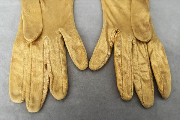 Detail view of 1950s vintage wrist length metallic gold nylon gloves. Approximately size 5. Showing a close-up of the lighter fingers and palm where some of the metallic finish has rubbed away.