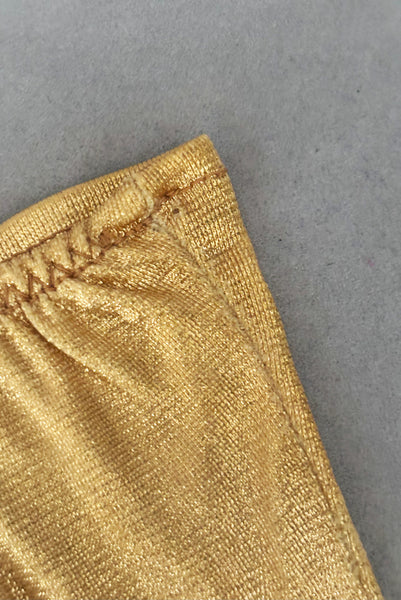 Detail view of 1950s vintage wrist length metallic gold nylon gloves. Approximately size 5. Showing a small hole at the wrist of one glove where a tag once was.