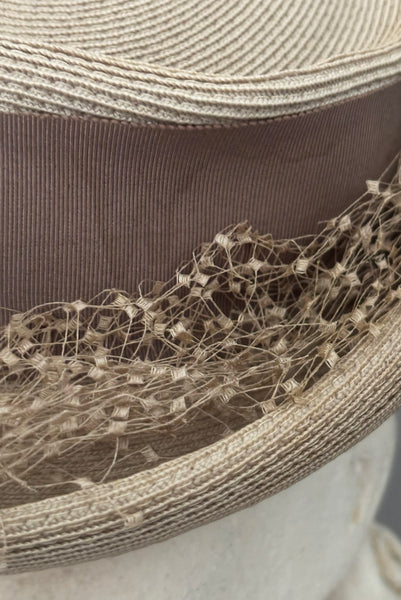Detail view of 1940s vintage taupe straw riding style tilt topper hat with matching petersham ribbon and veiling trim, by Marche. Showing the brittle veiling and a water mark on the petersham ribbon.