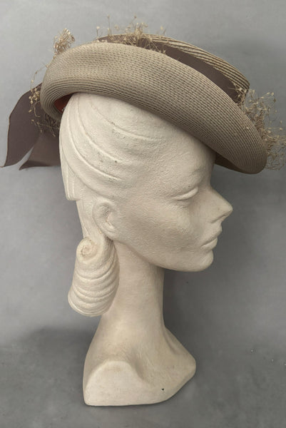 Vertical side view of 1940s vintage taupe straw riding style tilt topper hat with matching petersham ribbon and veiling trim, by Marche.